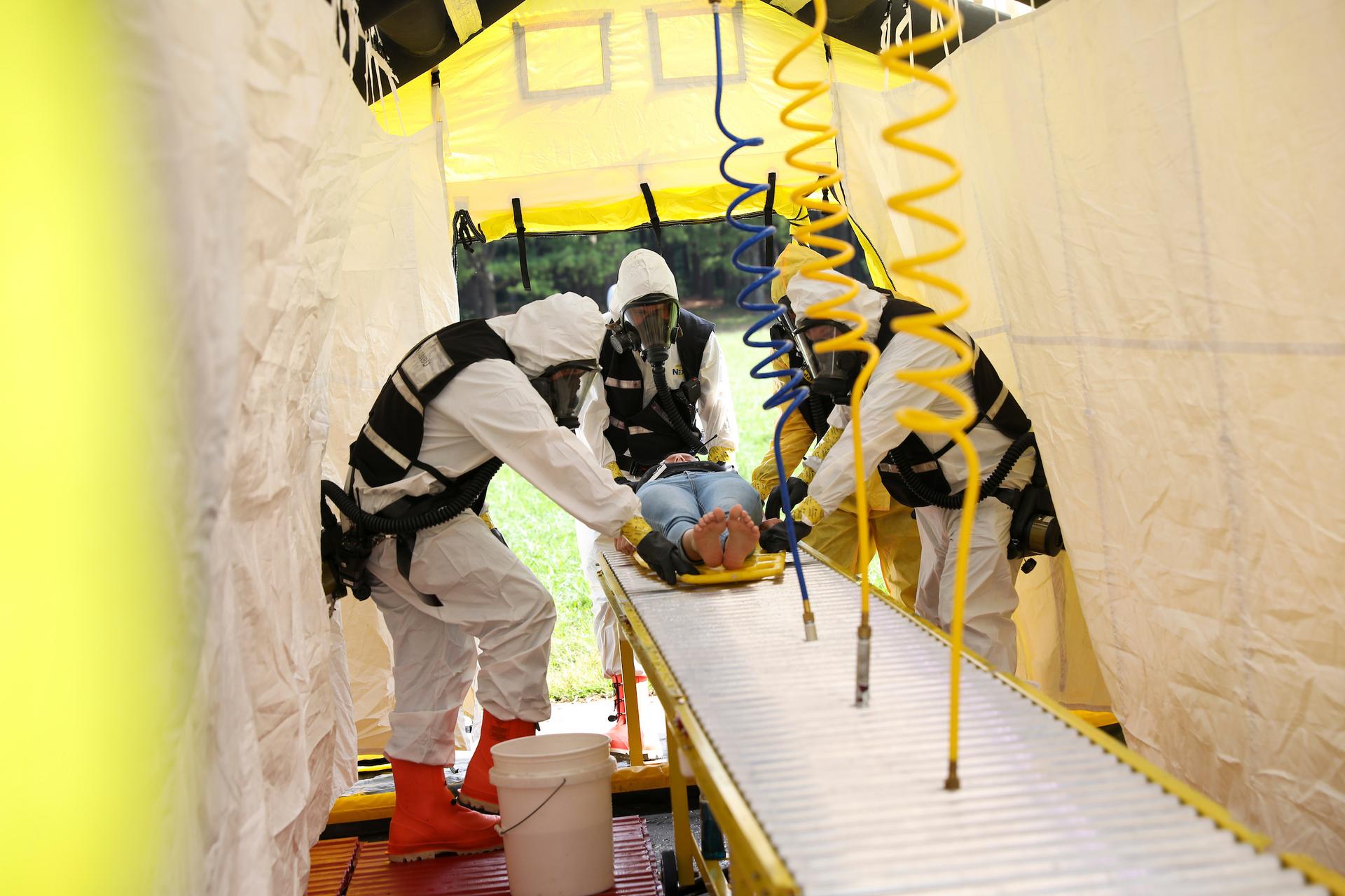 emergency workers in protective gear working on a patient 