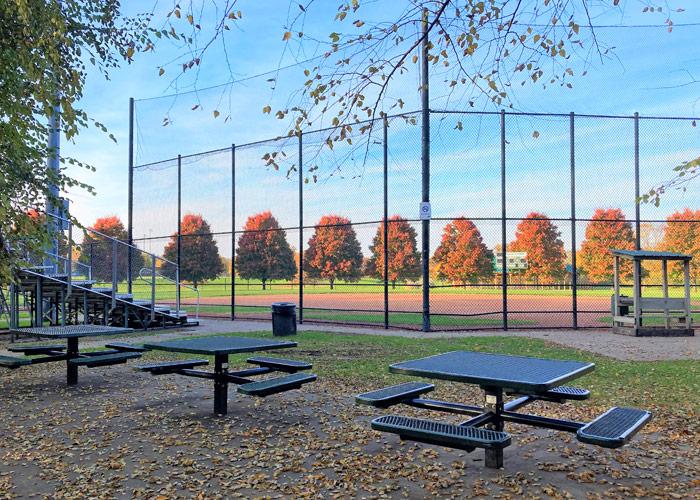 Picnic tables and stands next to a baseball field at a park